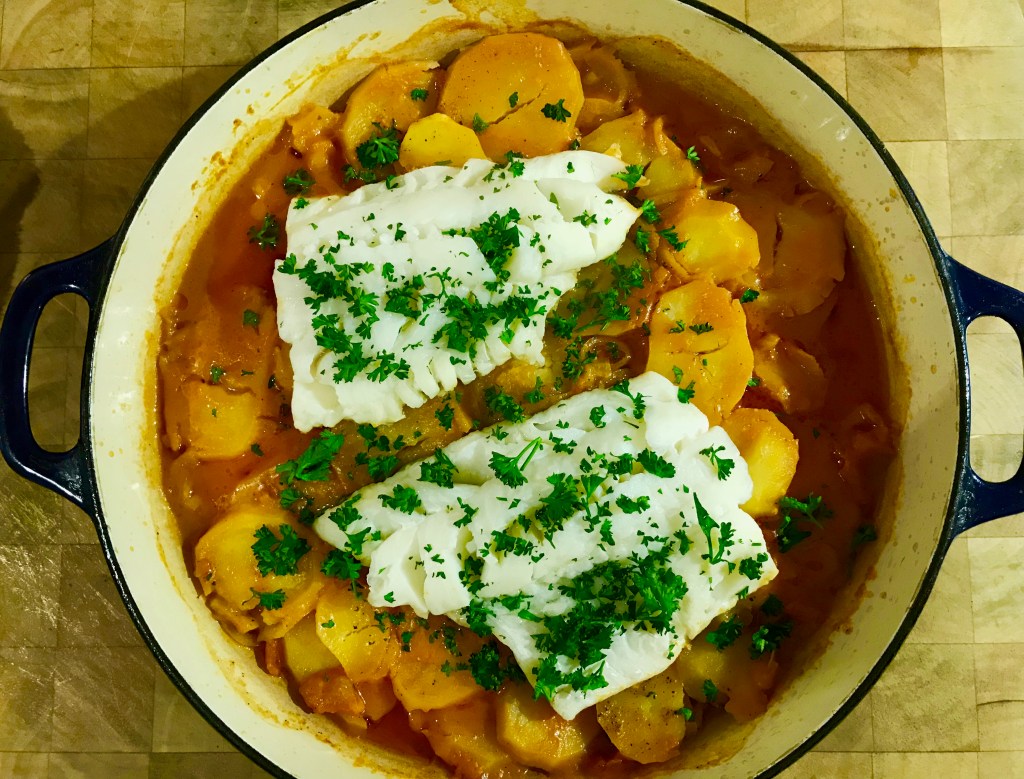Baked cod on a braise of potatoes, garlic and&nbsp;tomatoes